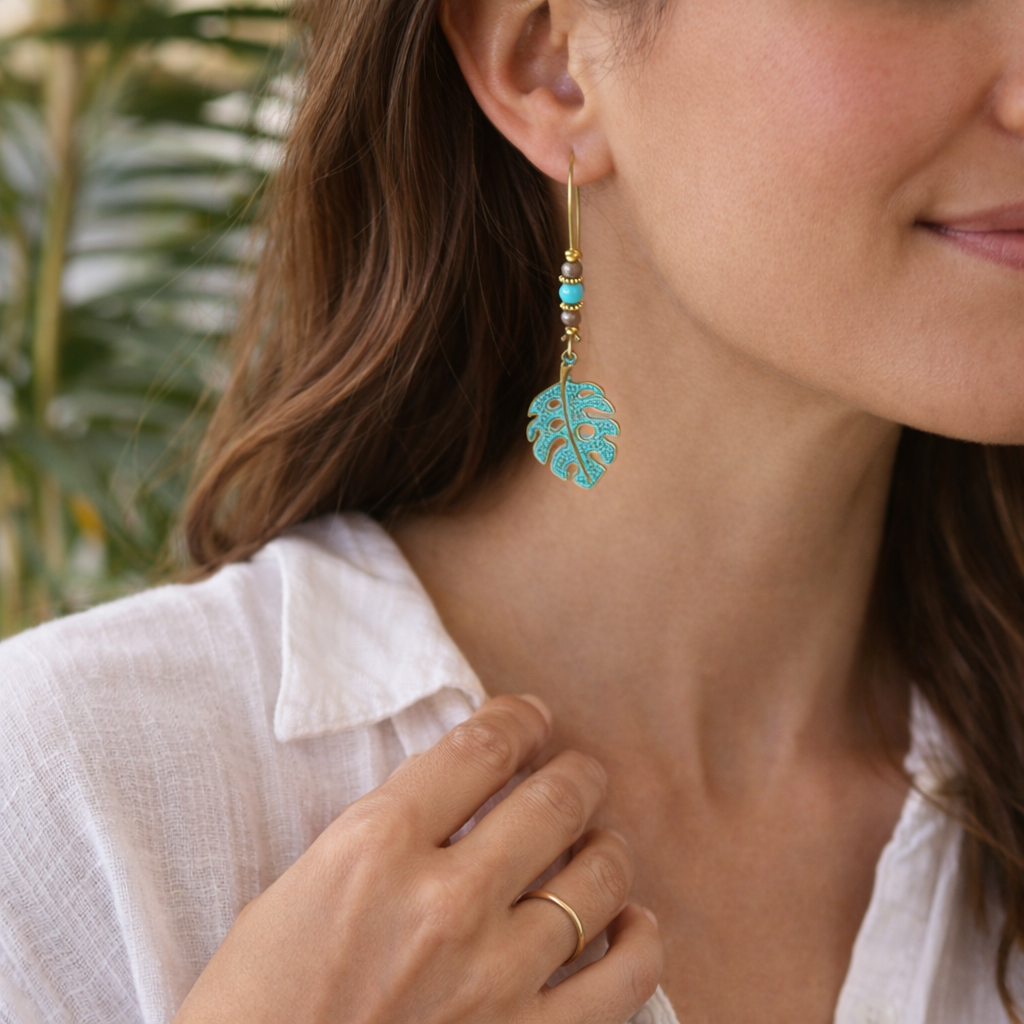 Close-up of a woman wearing turquoise leaf-shaped earrings with a blurred natural background