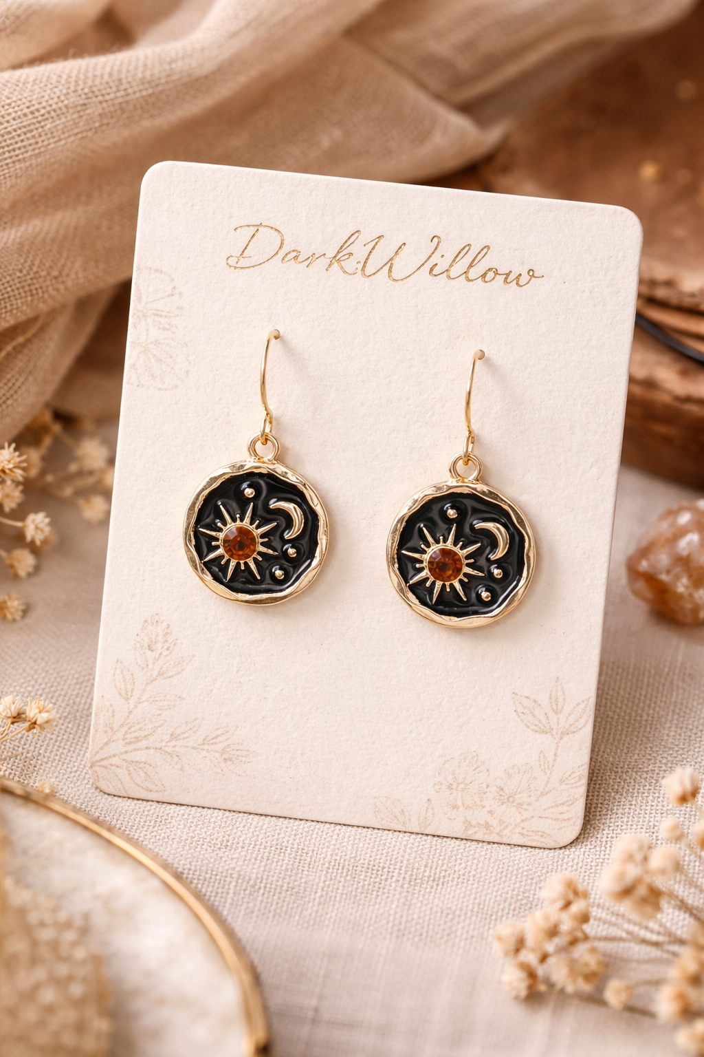 Pair of celestial-themed earrings on a 'Dark Willow' branded card with a beige background.