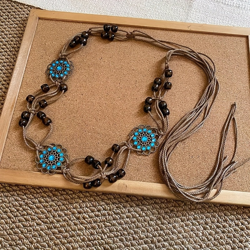 Necklace with blue floral designs and black beads on a textured surface