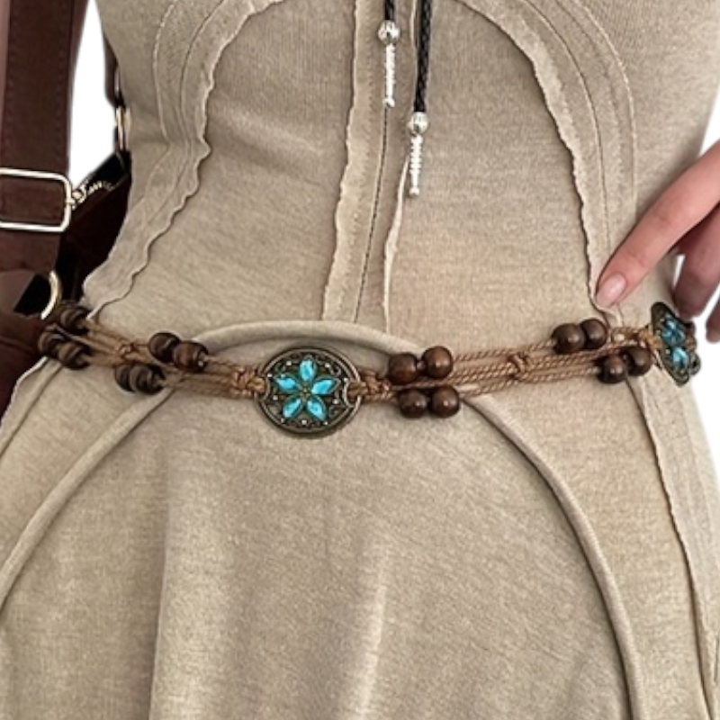 Close-up of a decorative belt with turquoise stones and wooden beads on a beige outfit.