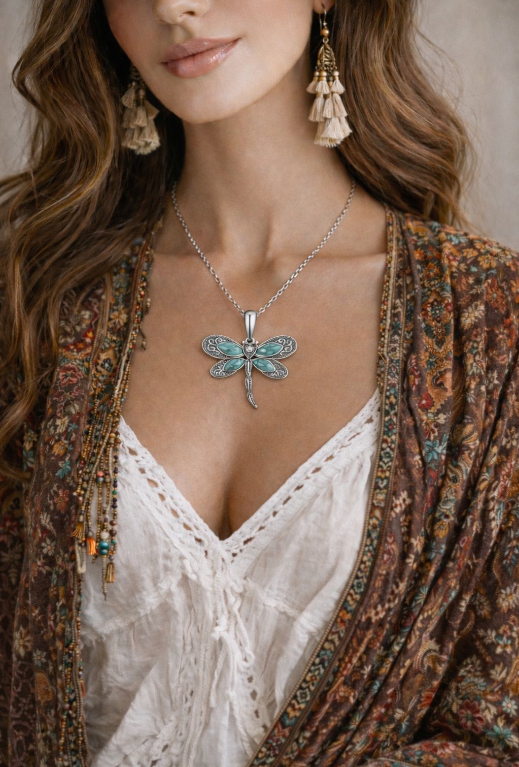 Woman wearing a dragonfly necklace and earrings with a patterned cardigan.