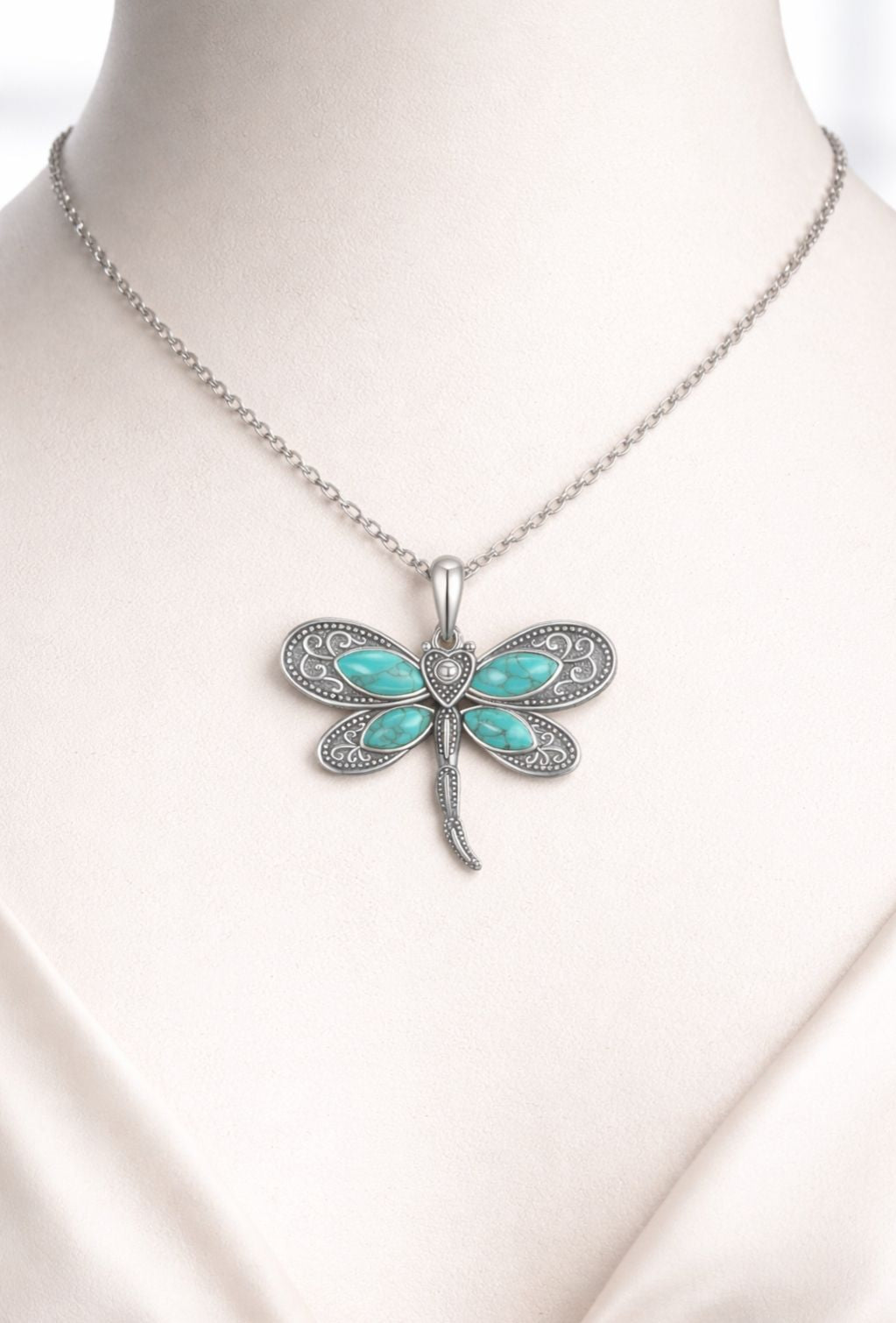 Dragonfly-shaped pendant necklace with turquoise stones on a mannequin.